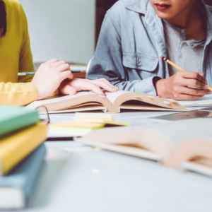 two girls studying, in front of them are beeoks, they are writing something down